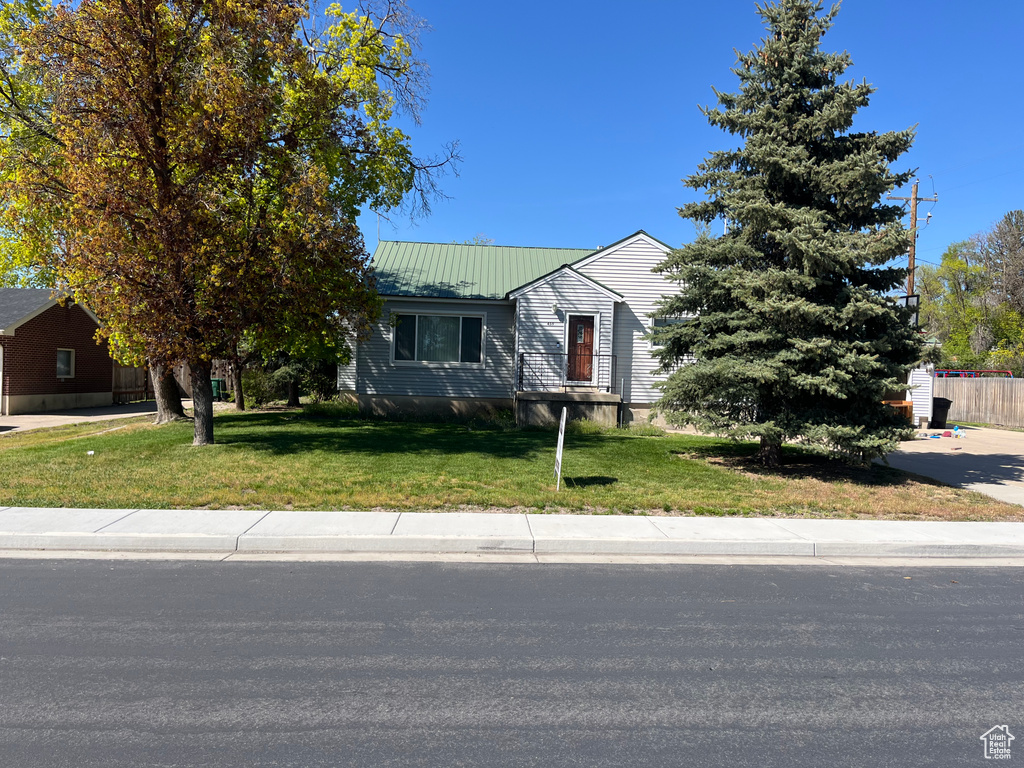 View of property hidden behind natural elements featuring a front yard and metal roof