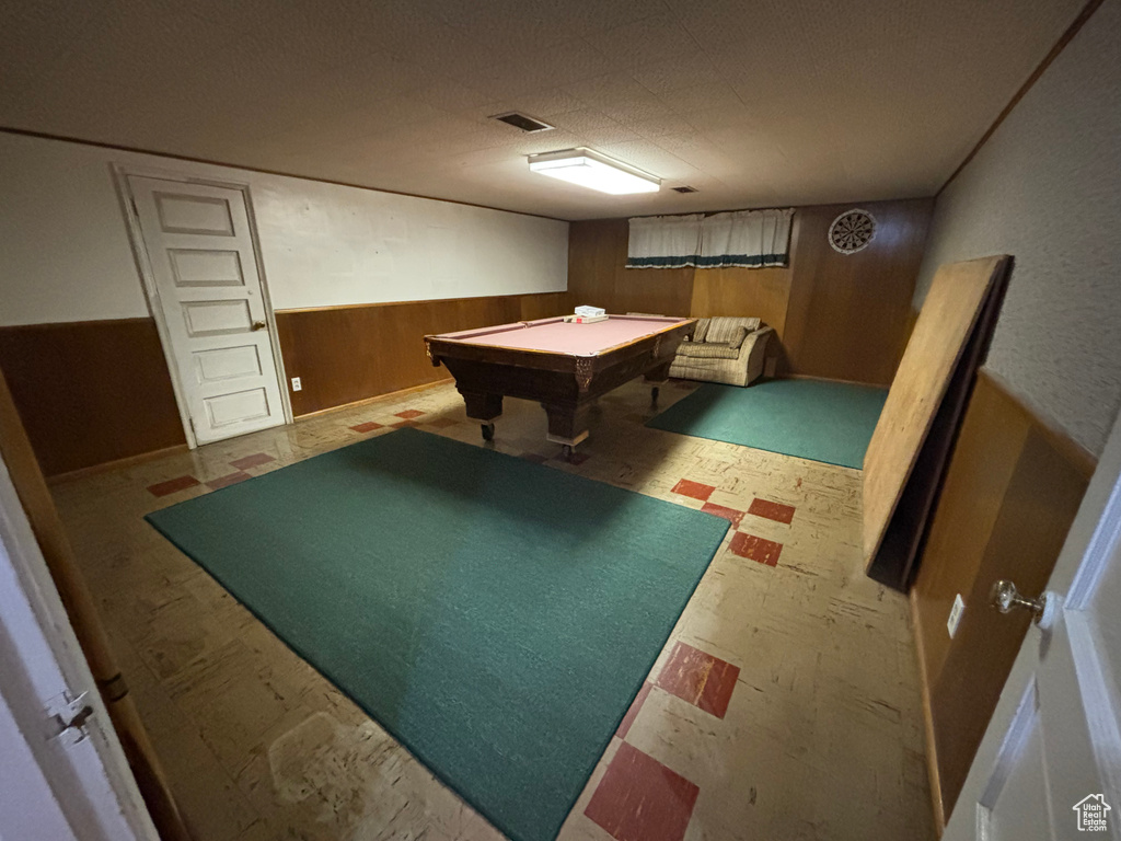 Rec room with wooden walls, billiards table, tile patterned floors, and a wainscoted wall