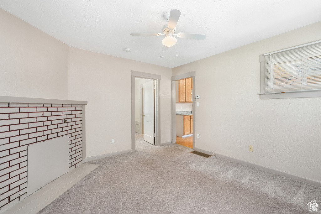 Unfurnished living room with baseboards, ceiling fan, visible vents, and light carpet