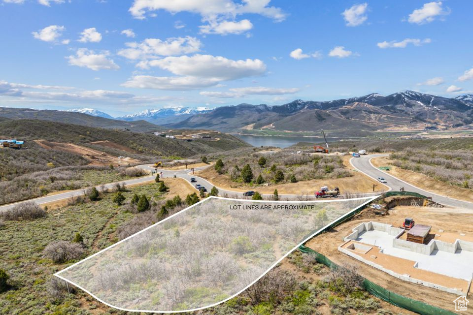 Aerial view of property and surrounding area featuring property boundaries highlighted and a water and mountain view