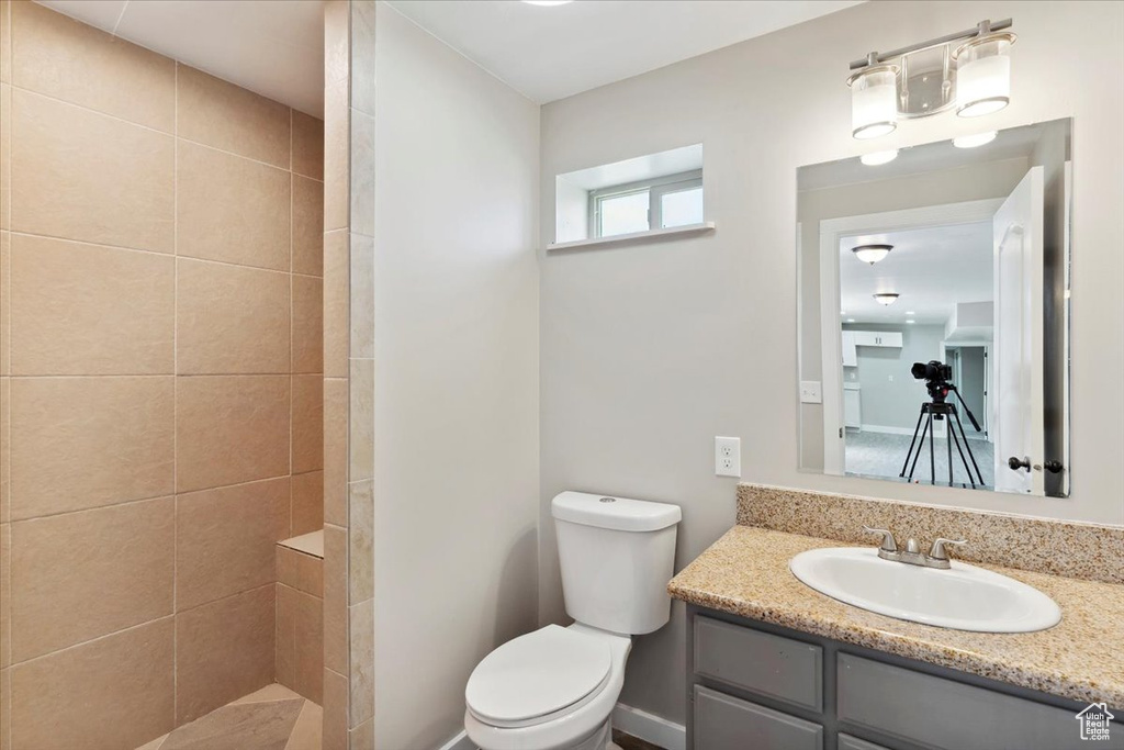 Full bathroom featuring toilet, a tile shower, and vanity