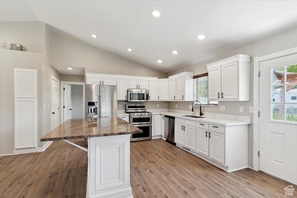 Kitchen with appliances with stainless steel finishes, lofted ceiling, a sink, light wood-style flooring, and plenty of natural light