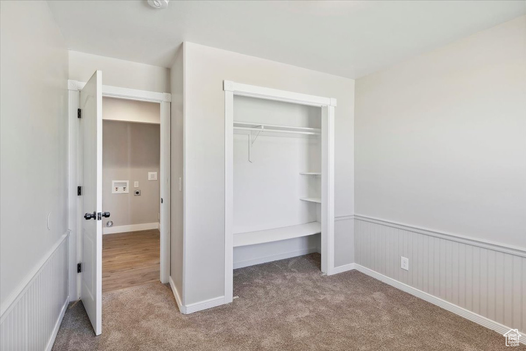 Unfurnished bedroom featuring carpet flooring, a closet, and a wainscoted wall
