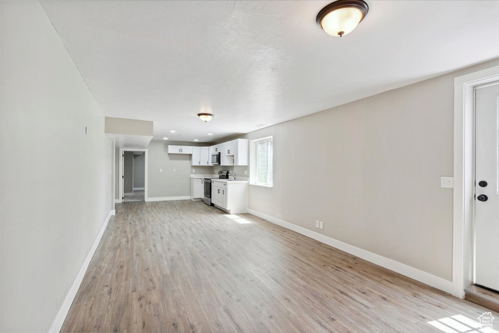 Unfurnished living room with light wood-style floors and baseboards