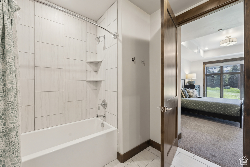 Ensuite bathroom with baseboards, shower / tub combo, tile patterned floors, and a raised ceiling