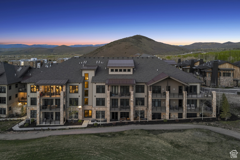 Rear view of property featuring stone siding, a mountain view, and a shingled roof