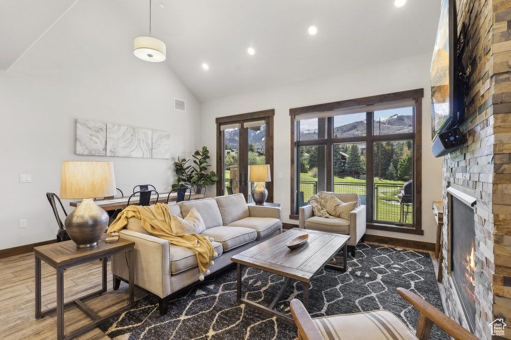 Living area with recessed lighting, high vaulted ceiling, wood finished floors, baseboards, and a fireplace