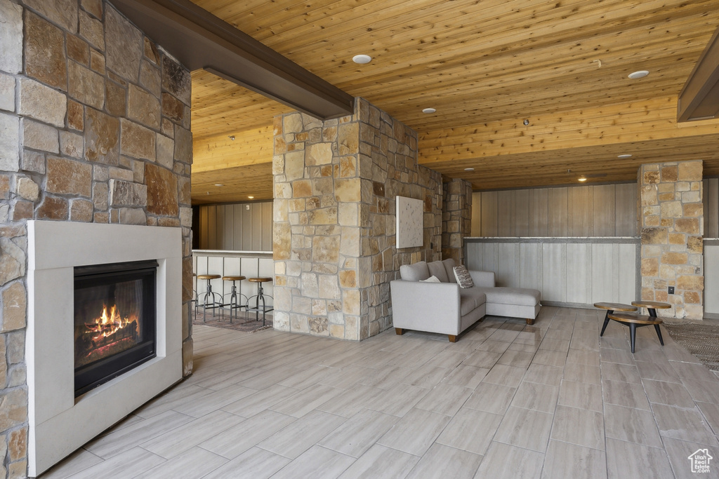 Unfurnished living room featuring an outdoor stone fireplace and wooden ceiling