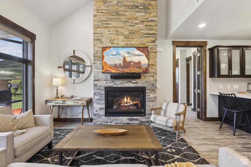 Living room featuring a fireplace, wood finished floors, baseboards, and high vaulted ceiling