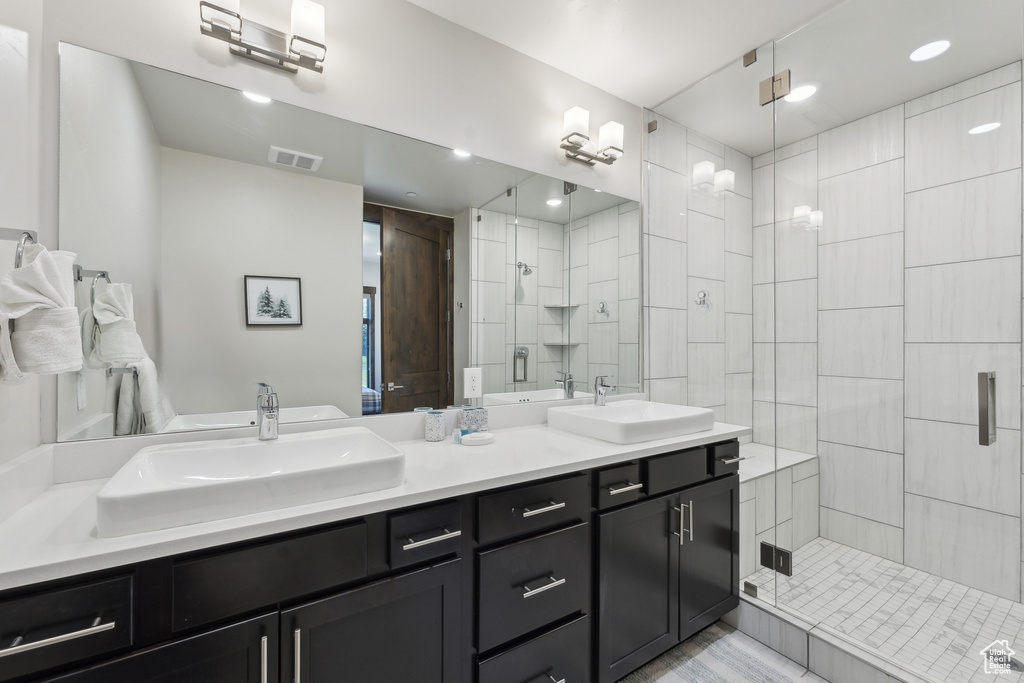 Full bathroom with a shower stall, double vanity, and recessed lighting