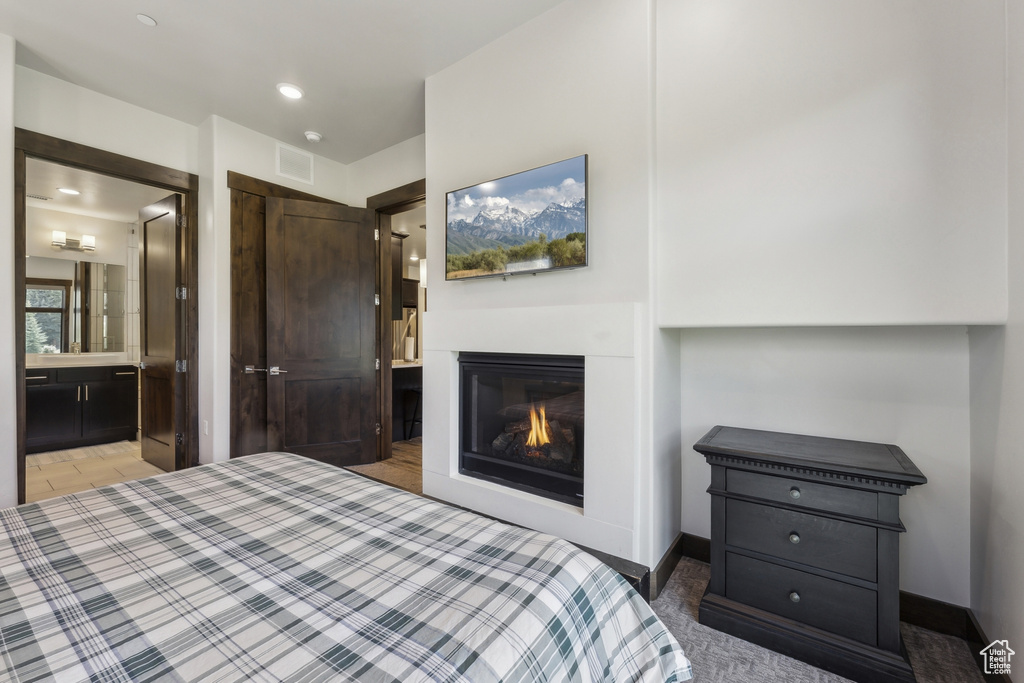 Bedroom featuring a glass covered fireplace and connected bathroom