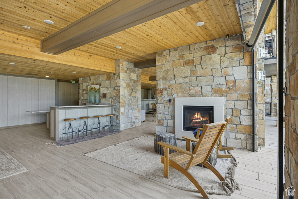 Sitting room featuring a bar, wood ceiling, an outdoor stone fireplace, and beamed ceiling
