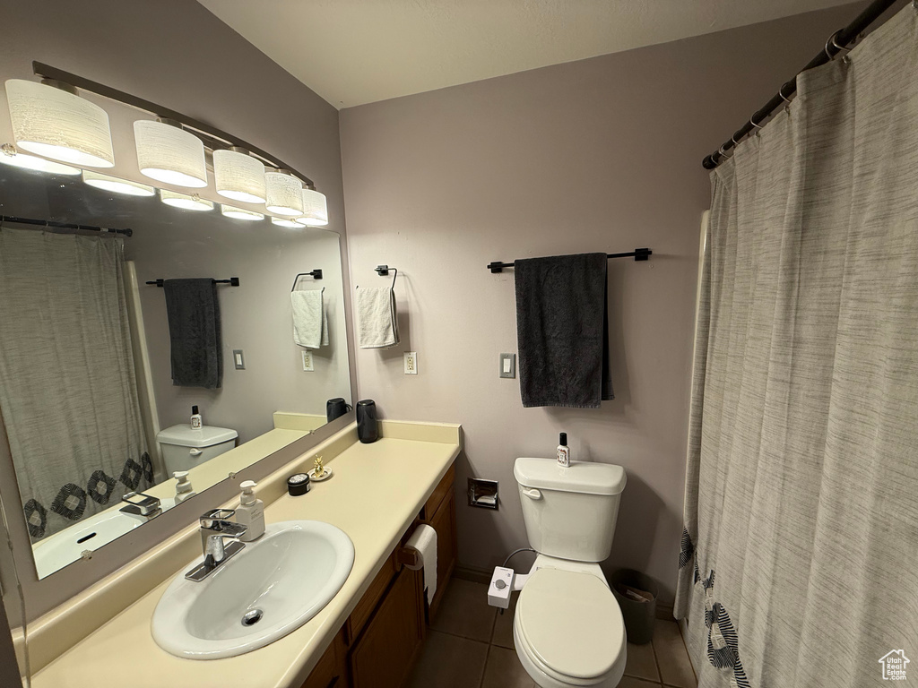 Full bath with toilet, tile patterned floors, vanity, and baseboards