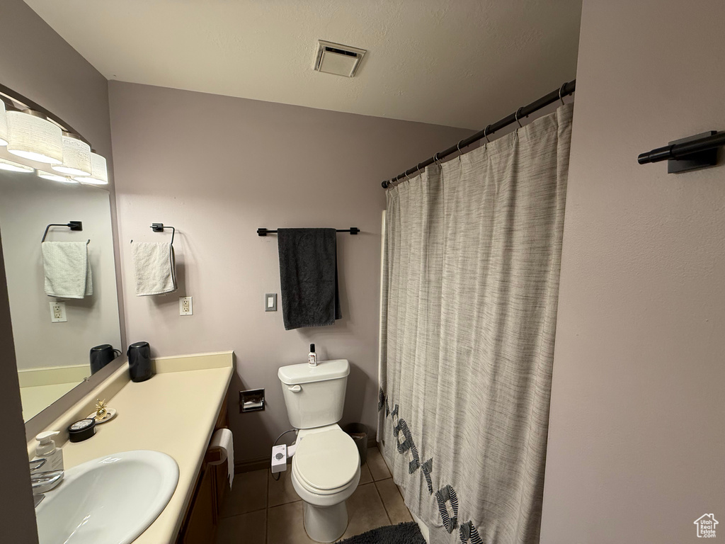 Full bathroom with tile patterned floors, toilet, vanity, and a shower with shower curtain
