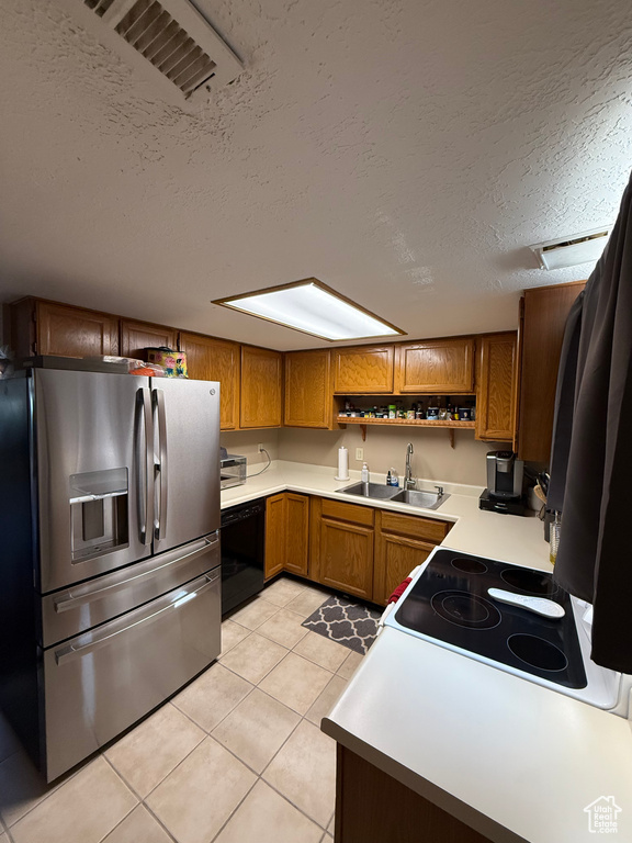Kitchen featuring stainless steel refrigerator with ice dispenser, a sink, a textured ceiling, black dishwasher, and brown cabinetry