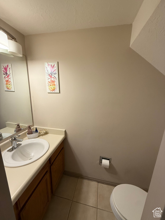 Half bath featuring vanity, tile patterned floors, toilet, and a textured ceiling
