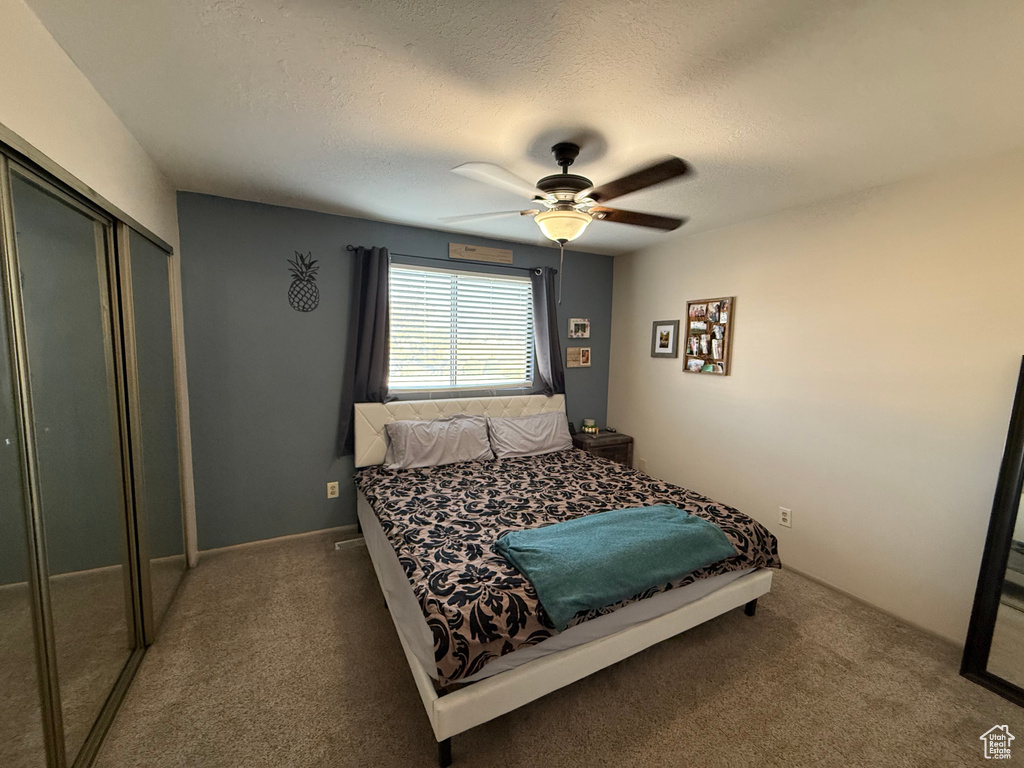 Bedroom with a closet, carpet, a textured ceiling, and a ceiling fan