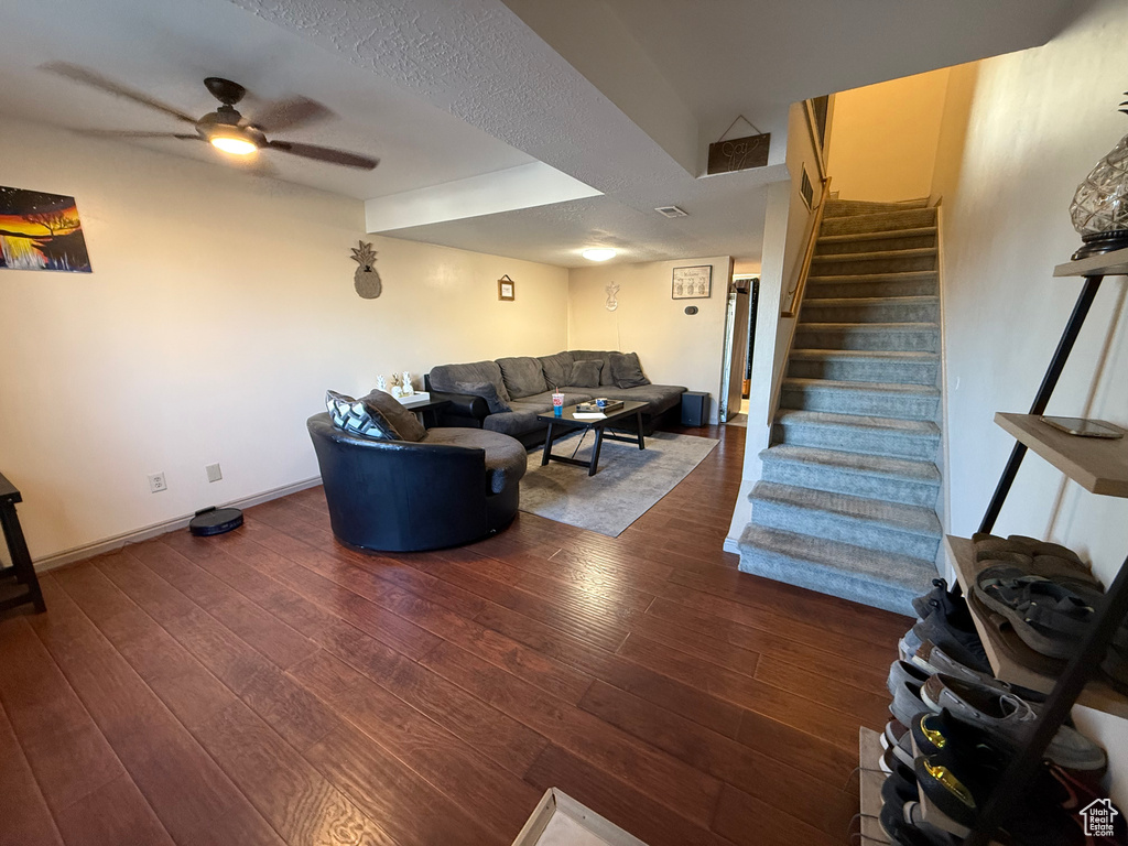 Living area featuring wood-type flooring, stairway, a ceiling fan, and baseboards