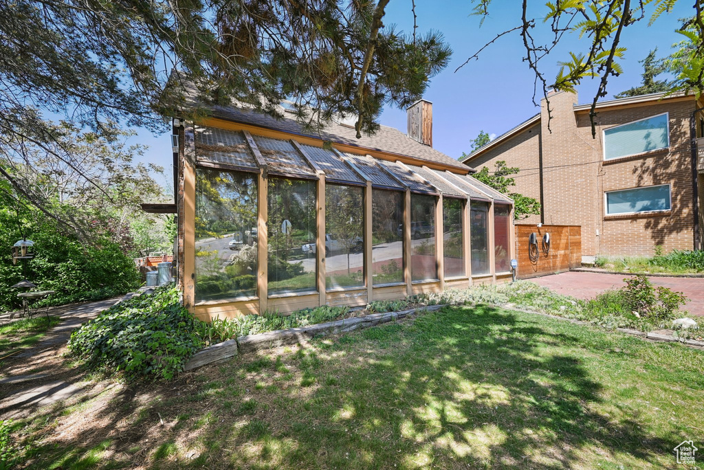 View of green lawn with a greenhouse and an outdoor structure