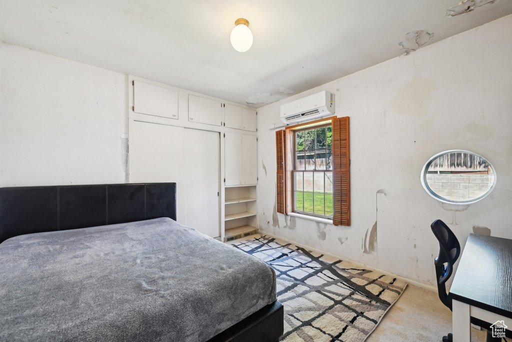 Bedroom featuring an AC wall unit, light carpet, and baseboards