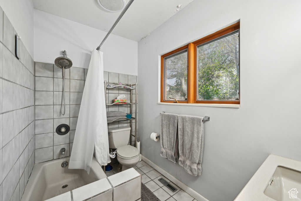 Bathroom with toilet, tile patterned flooring, a sink, and shower / bathtub combination with curtain