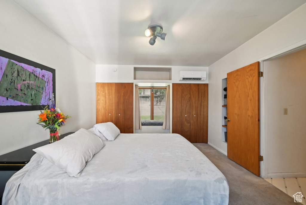 Bedroom featuring carpet floors, a wall mounted air conditioner, and two closets