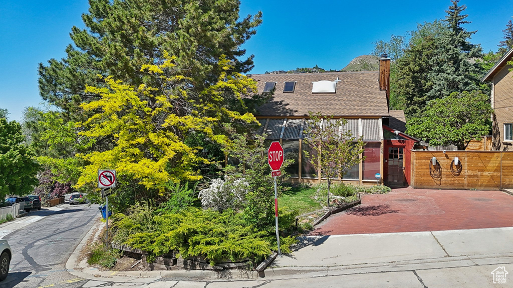 View of front of property featuring a chimney, roof with shingles, and fence