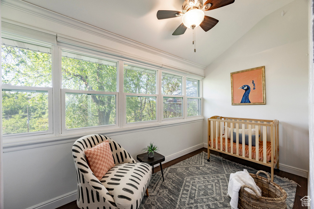 Bedroom with vaulted ceiling, baseboards, wood finished floors, a crib, and a ceiling fan
