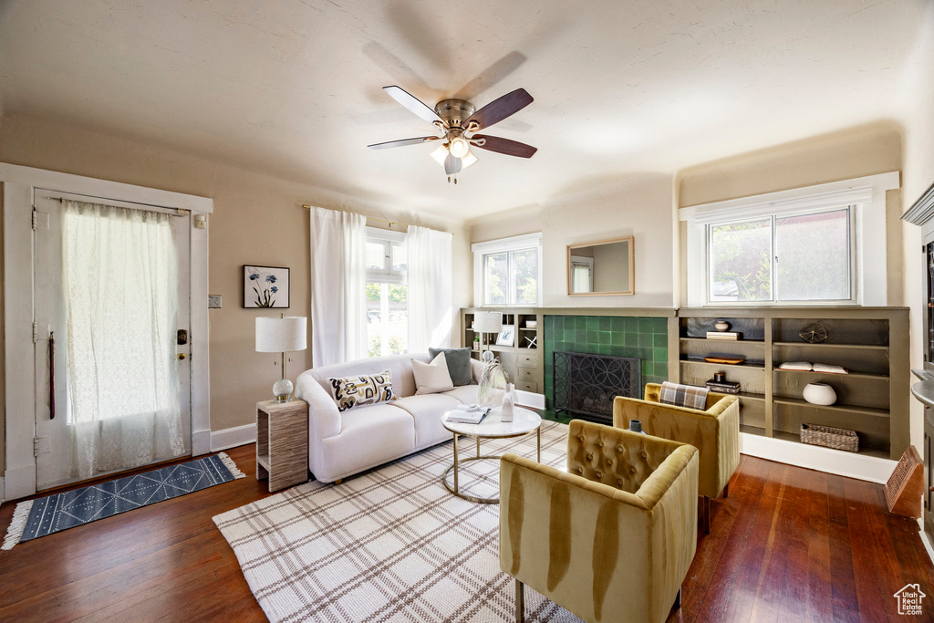 Living area featuring a tile fireplace, wood finished floors, a ceiling fan, and baseboards