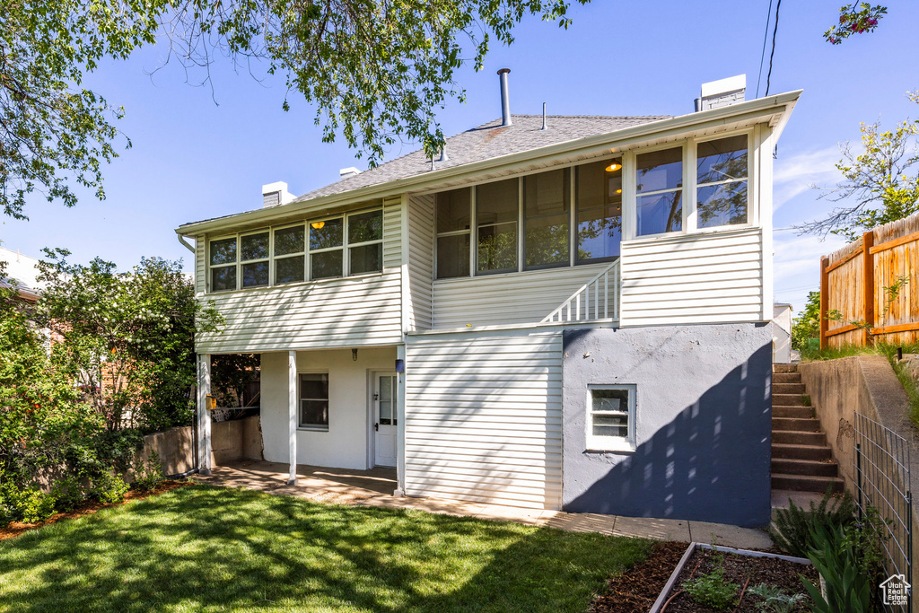 Back of house featuring a chimney, stairway, a sunroom, and stucco siding
