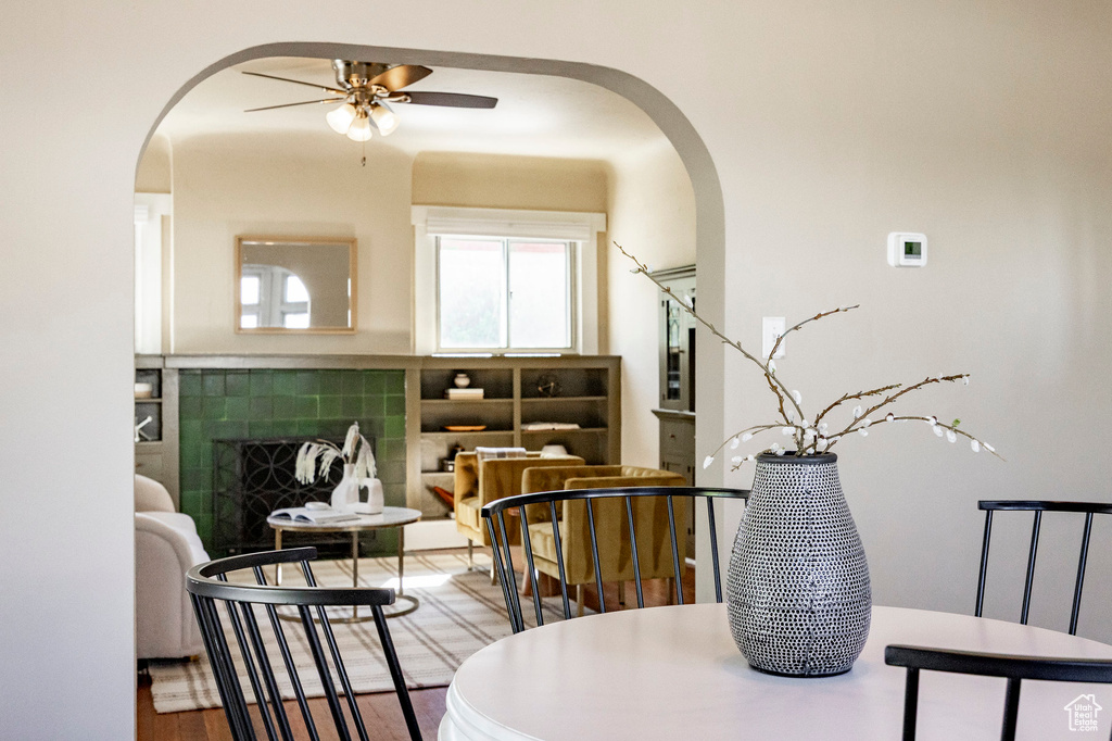 Sitting room featuring arched walkways, a fireplace, a ceiling fan, and wood finished floors