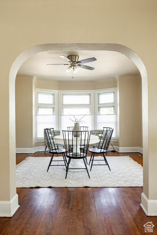 Dining space featuring arched walkways, hardwood / wood-style flooring, and ceiling fan