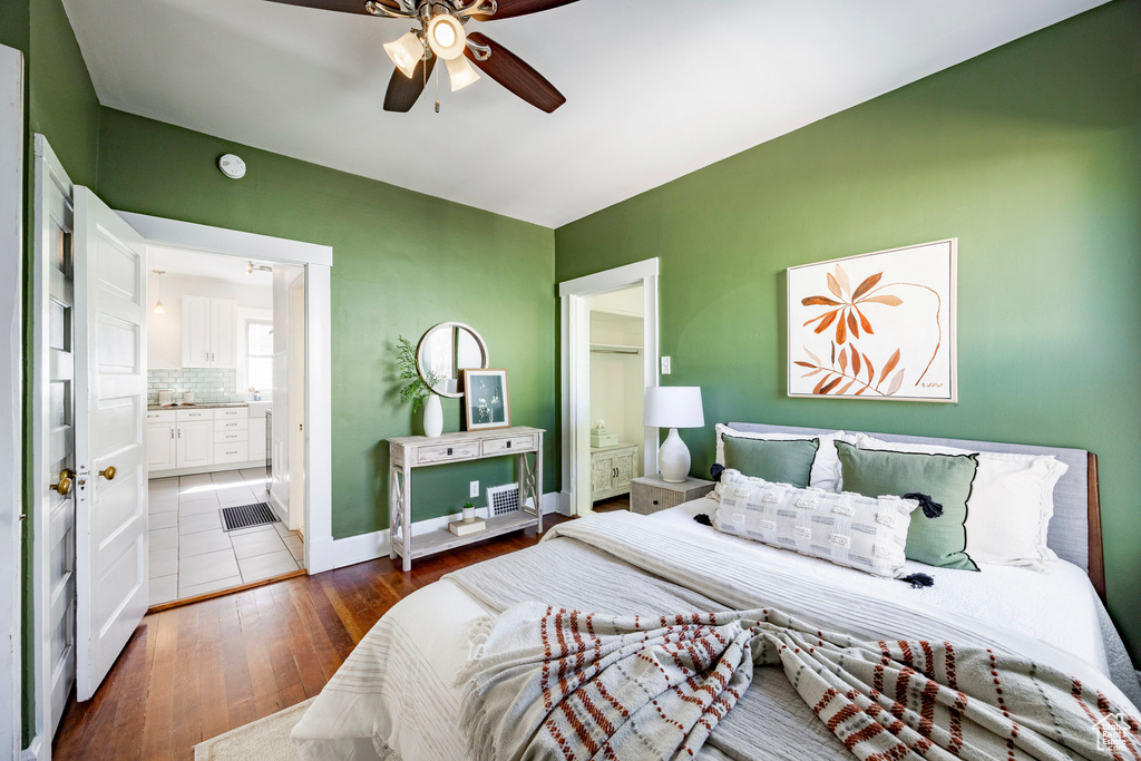 Bedroom with hardwood / wood-style flooring, connected bathroom, a ceiling fan, and baseboards