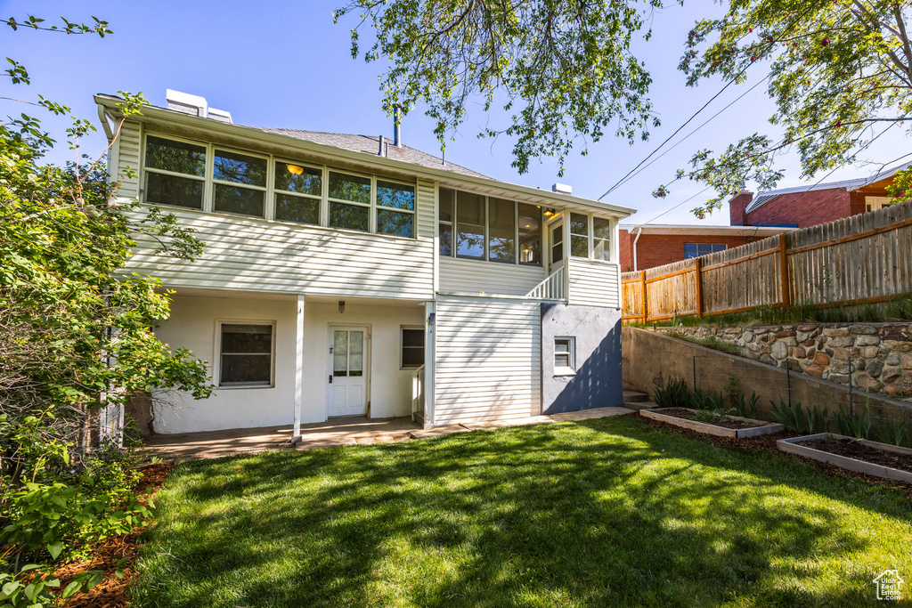 Rear view of property with a sunroom, a chimney, a garden, and a patio area