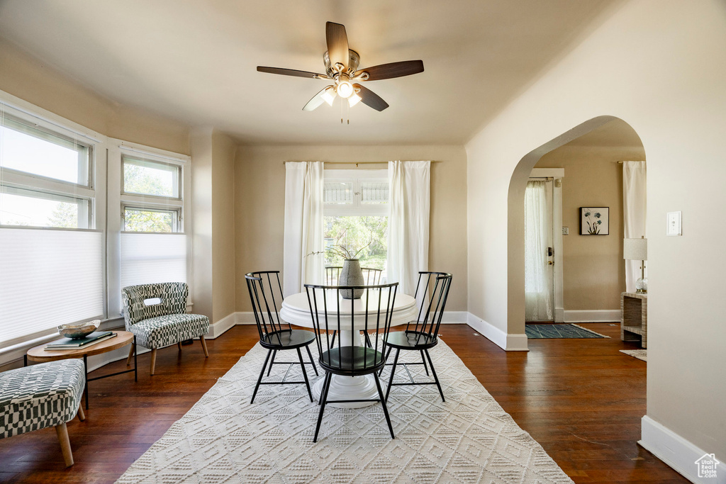 Dining space with arched walkways, ceiling fan, baseboards, and wood finished floors
