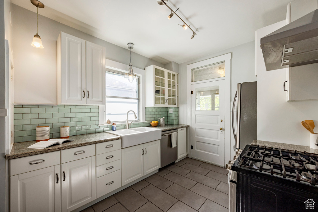 Kitchen with exhaust hood, appliances with stainless steel finishes, and white cabinetry