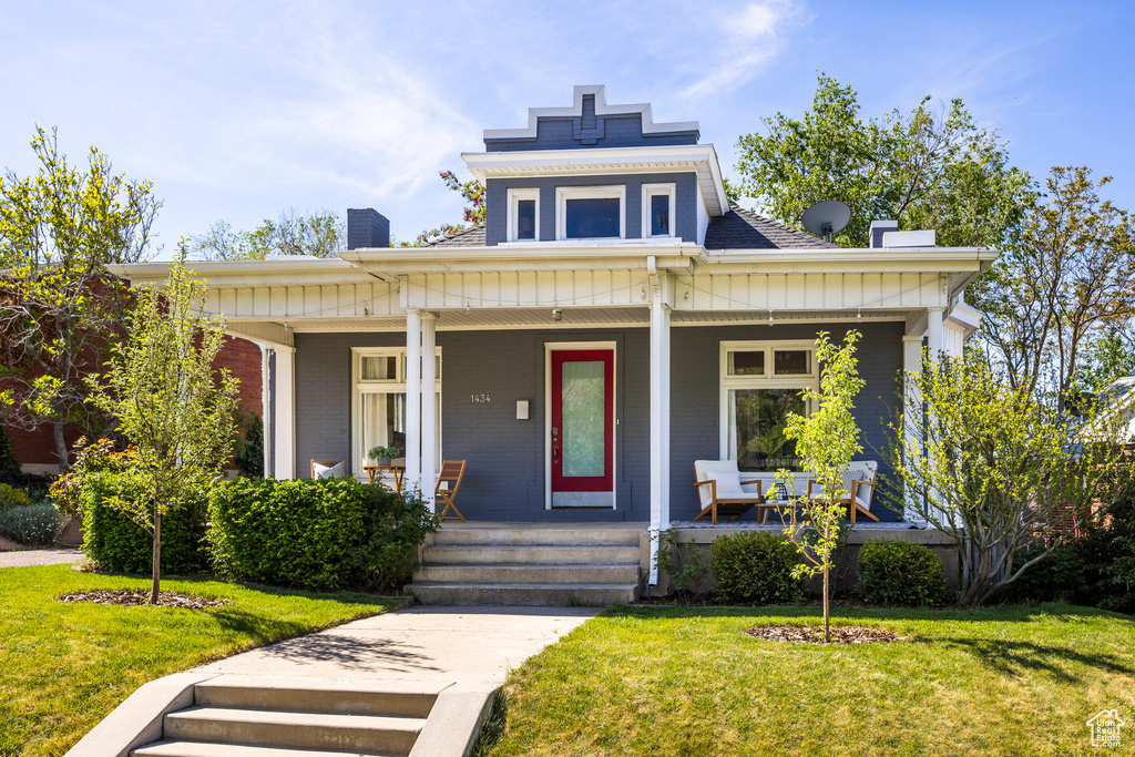 View of front of home featuring a chimney, a porch, board and batten siding, a front lawn, and a shingled roof