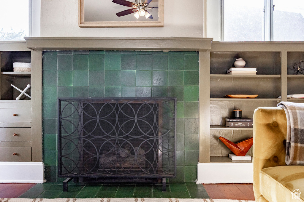 Detailed view of a fireplace, ceiling fan, and wood finished floors