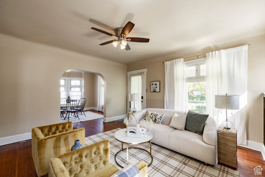 Living room with arched walkways, healthy amount of natural light, ceiling fan, and baseboards