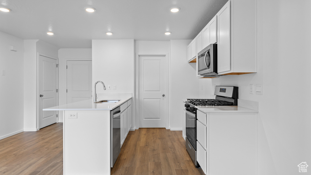 Kitchen featuring stainless steel appliances, a sink, wood finished floors, recessed lighting, and a peninsula