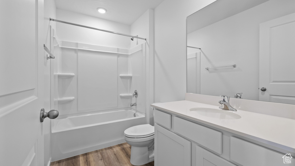 Full bathroom featuring wood finished floors, toilet, vanity, and shower / bath combination