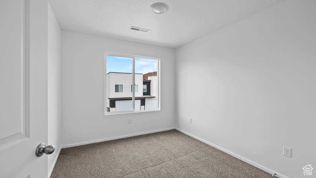 Carpeted spare room featuring baseboards