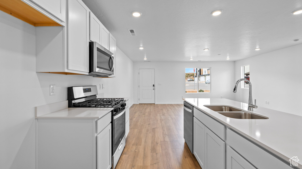 Kitchen featuring stainless steel appliances, a sink, light wood-style flooring, light countertops, and recessed lighting