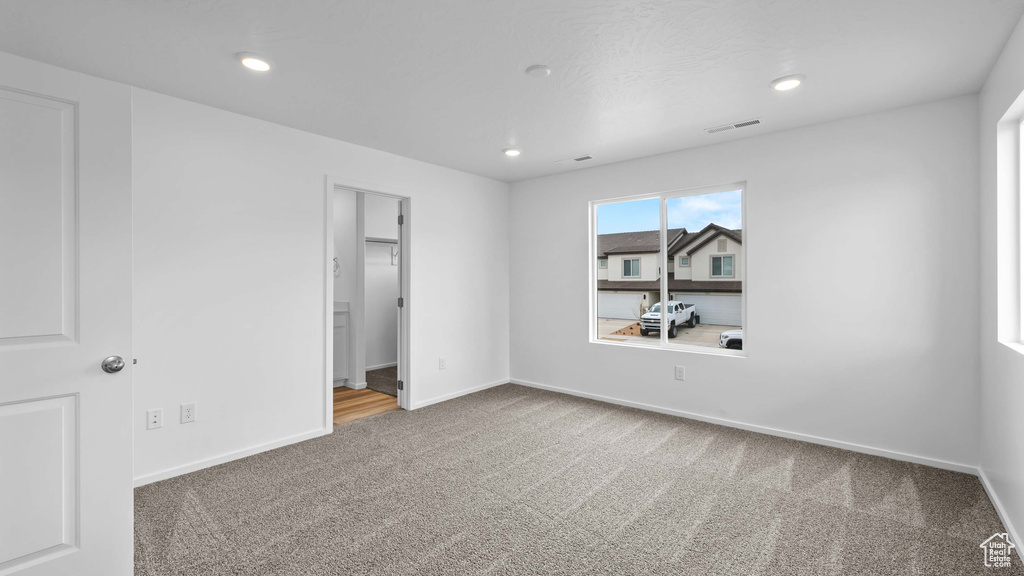 Unfurnished bedroom with carpet, baseboards, a walk in closet, and recessed lighting