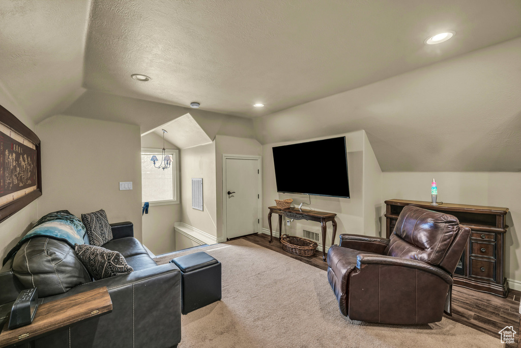 Living room featuring lofted ceiling, recessed lighting, baseboards, and a textured ceiling