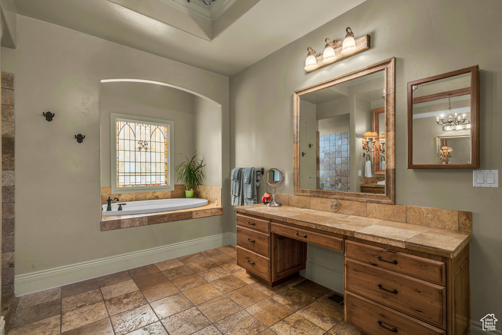 Bathroom with stone tile floors, a garden tub, vanity, and baseboards