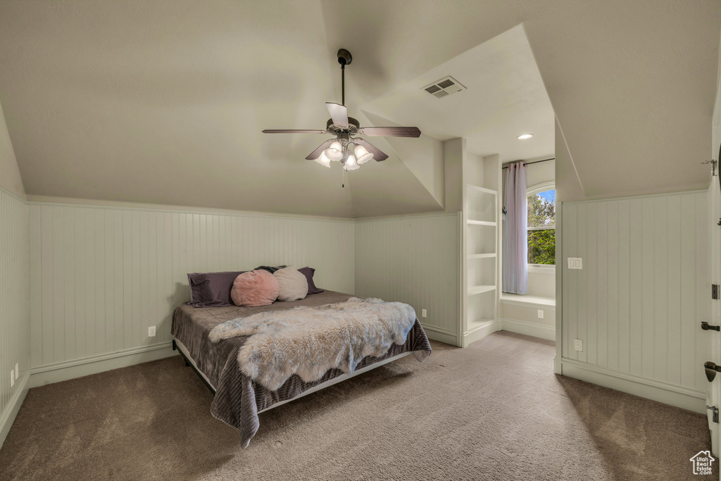 Carpeted bedroom featuring lofted ceiling, wainscoting, ceiling fan, and baseboards