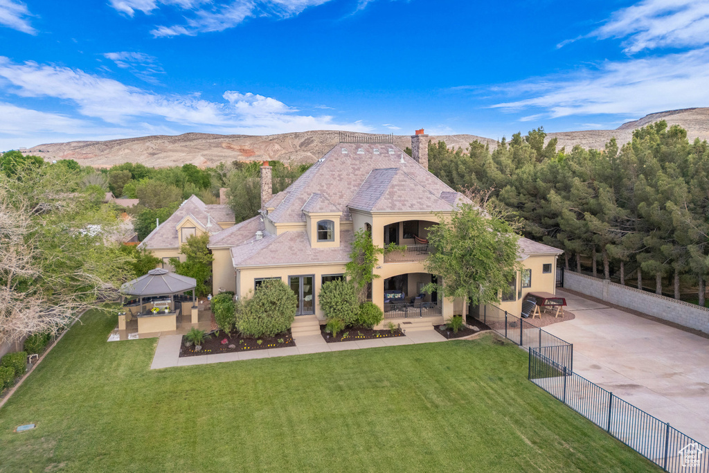 View of front of house with a gazebo, a chimney, a balcony, stucco siding, and a patio