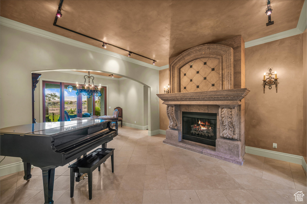 Living area with track lighting, a chandelier, arched walkways, a fireplace, and ornamental molding
