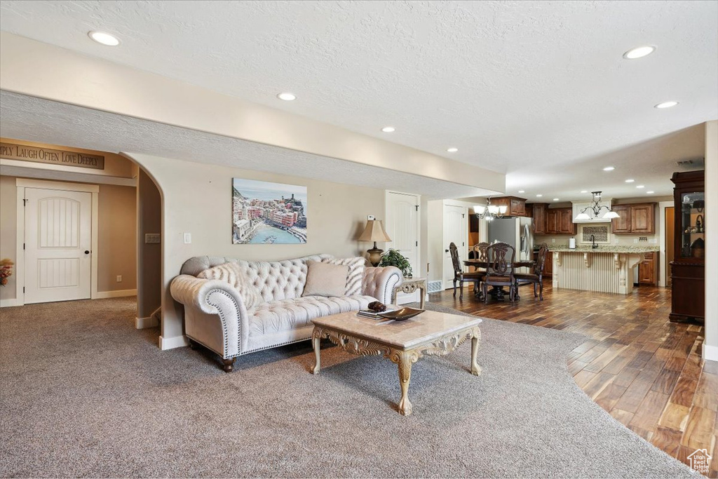 Living area with recessed lighting, arched walkways, dark wood-style floors, a textured ceiling, and baseboards